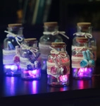 Close-up of glowing glass wish bottles with LED lights, lace ribbons, and cork stoppers