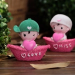 Detail of cute resin couple figurines in boats with pink hearts and LOVE and MISS text