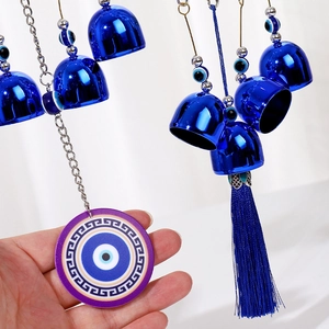Detailed close-up of Evil Eye wind chime featuring blue bells and long silk tassels