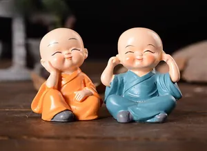 Close-up of two cute resin monk figurines in orange and blue robes on a wooden desk