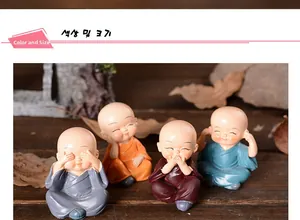 Close-up of four cute resin monk figurines in colorful robes on a dark wooden base