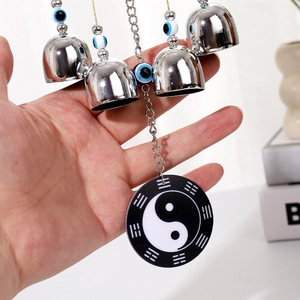 Detail of hanging evil eye wind chime with silver metal bells and ying yang pendant