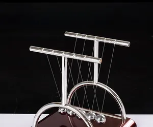 Macro side view of Newton's cradle with chrome balls and mirror base on black backdrop