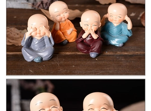 Detailed view of four small zen monk figurines in colorful robes on a wooden surface