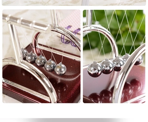 Detail of silver Newton's cradle balls and curved metal stand on dark red base