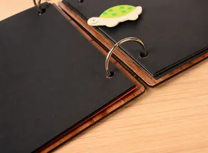 Close-up of wooden heart photo album with silver loose-leaf rings and black paper pages