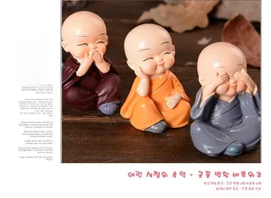 Three cute resin monk figurines in colorful robes on a warm wooden background decor