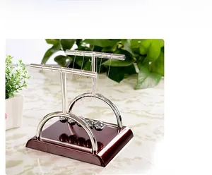 Macro detail of polished Newton's cradle balls with silver T-frame and wooden base