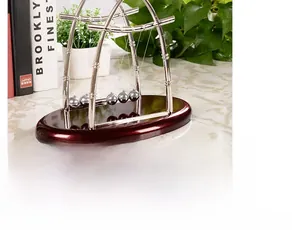 Pendule de Newton avec cinq billes d'acier sur socle rouge sur surface de marbre