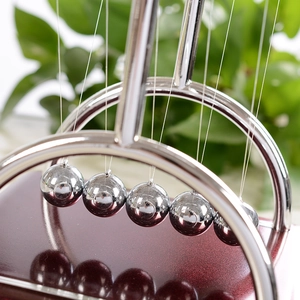 Newton's Cradle balance balls with chrome curved frame and polished red wood base