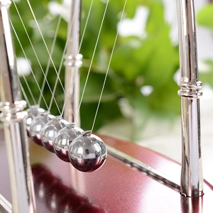 Pendule de Newton avec billes métalliques et socle en acajou sur un bureau de bureau