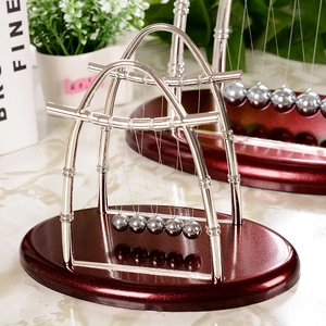 Pendule de Newton avec cinq billes en acier sur une arche élégante et socle rouge