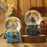 Detailed view of Minions theme crystal ball ornament with sculpted blue base on wood