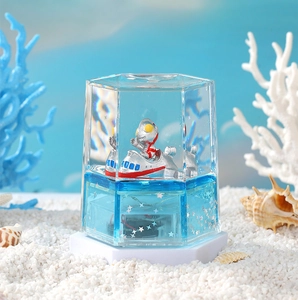 Close-up of Ultraman figure in blue liquid hourglass with silver star glitters and shells