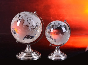 Detailed close-up of two crystal globes with frosted world map on silver metal stands