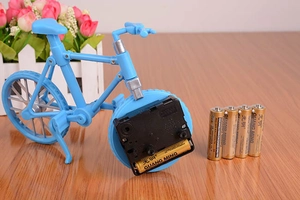 Kreative blaue Fahrrad-Tischuhr mit AA-Kohle-Zink-Batterien auf einem Holztisch