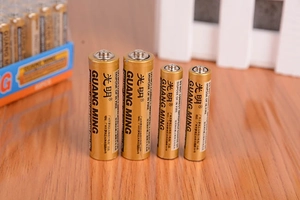 Nahaufnahme von AA- und AAA-Kohle-Trockenbatterien in Goldoptik auf Holzoberfläche