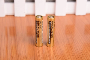 Detailansicht von zwei Guang Ming AAA R03 1,5V Kohlebatterien auf einer Holzoberfläche