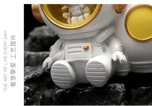 Close-up of a white and gold astronaut figurine sitting on a moon-like rock surface
