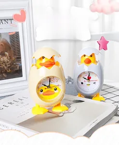 Detail view of cartoon eggshell chick and duckling alarm clocks on a cozy desk setup