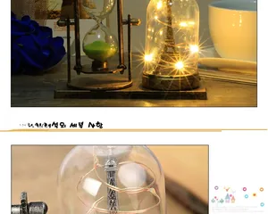 Dettaglio della clessidra vintage e lampada Torre Eiffel con calde luci LED e sabbia