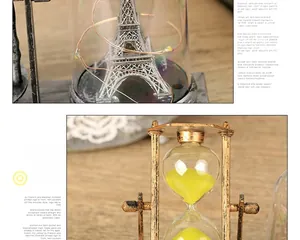 Dettaglio della torre Eiffel luminosa in vetro e clessidra in bronzo con sabbia gialla