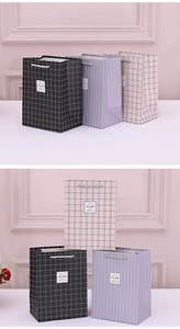 Detail of colorful geometric gift bags with white rope handles and quote labels