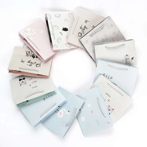Overhead view of assorted colorful paper gift bags with cartoon designs and rope handles