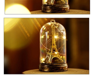 Detailed close-up of Eiffel Tower glass dome light with warm LED copper string lights