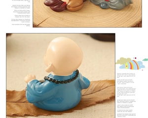 Macro detail of monk figurine in blue robe with prayer beads on wooden base