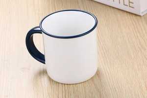 Top-down view of retro style white ceramic mug with blue rim on wooden surface