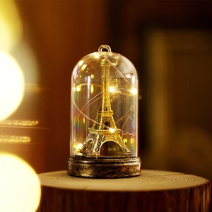 Vintage Eiffel Tower glass dome light with warm LED glow on a rustic wooden base