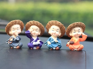 Detail of four resin monk figurines wearing straw hats for car and desk decoration