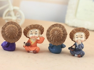 Detailed close-up of four resin monk figurines wearing straw hats for car decor