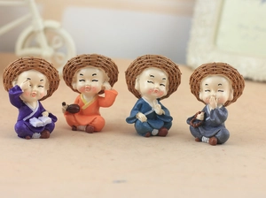 Detail of four creative resin monk figurines with straw hats for car dashboard decoration
