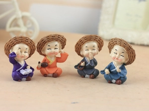 Set of four resin monk figurines with straw hats in various poses and colors