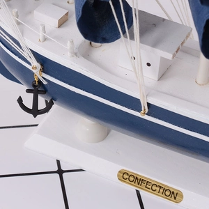 Detail of Mediterranean wood sailboat model with blue and white hull and metal nameplate