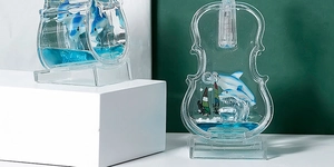 Macro shot of blue liquid violin ornament featuring mini dolphin and surfing scenes