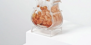 Detailed view of violin-shaped acrylic ornament with gold figurines and glitter flakes