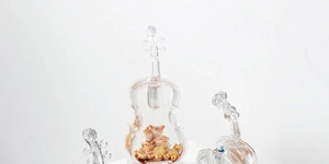 Detailed view of creative violin-shaped liquid decor with cute cats and golden coins inside