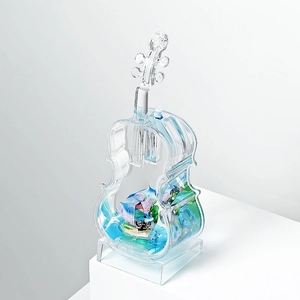Blue liquid-filled violin sculpture with miniature sailing boat and ocean scenery