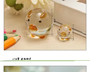 Detail view of 3cm and 1.7cm transparent crystal glass pigs with amber accents