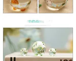 Close-up of small glass pigs with green floral details on white books for desk decor