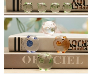 Colorful miniature glass pig figurines displayed on a book for desk decoration