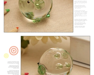 Detailed macro shot of a transparent glass pig ornament with green accents on linen