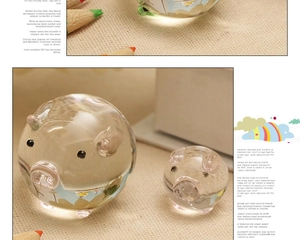 Close-up of two transparent crystal glass pig figurines with pink nose details and hand-painted art
