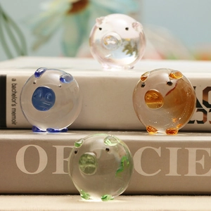 Set of four colorful mini crystal glass pig figurines displayed on books for desk decor
