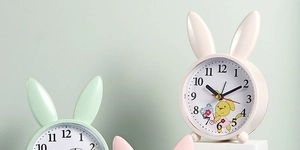 Detail of cute rabbit bedside clocks in cream and green with silent analog dials
