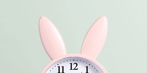Close-up of pink rabbit alarm clock ears and white dial with black numeric markers