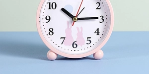 Close-up of pink rabbit alarm clock with clear black Arabic numerals and quiet sweep second hand